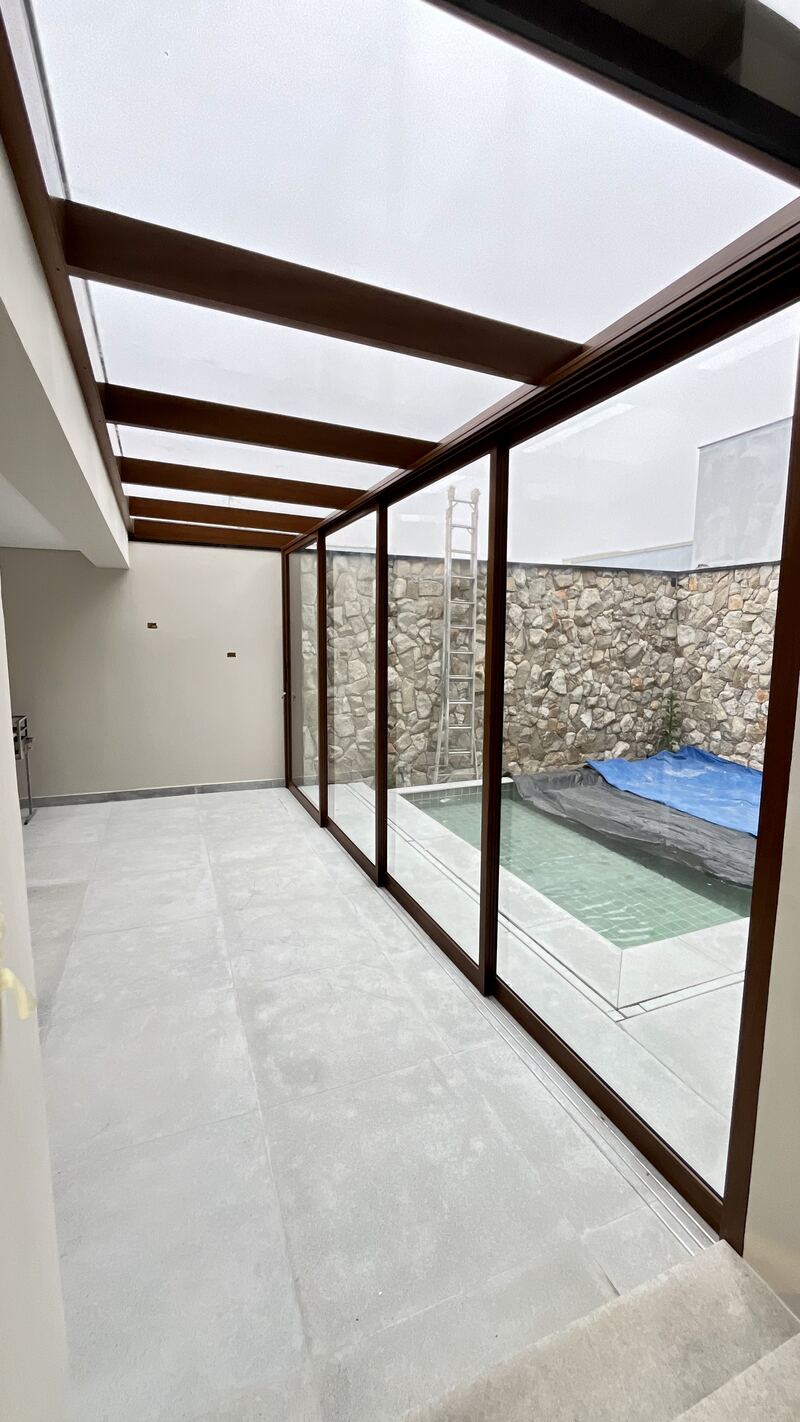 Cobertura e fechamento em vidro sobre área de piscina