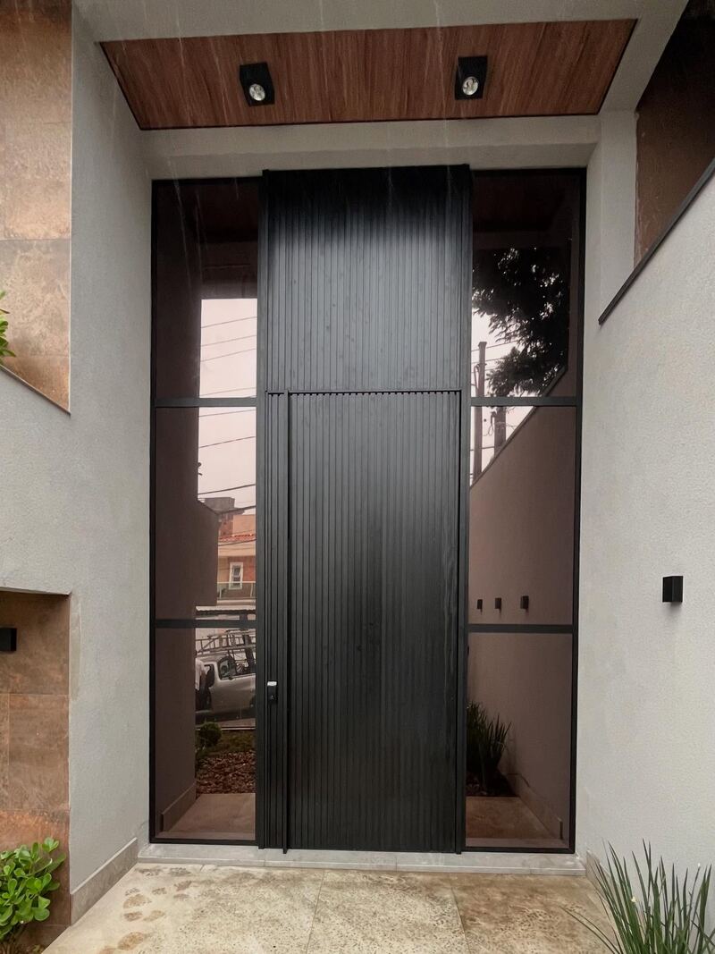 Porta pivotante de entrada em alumínio ripado escuro