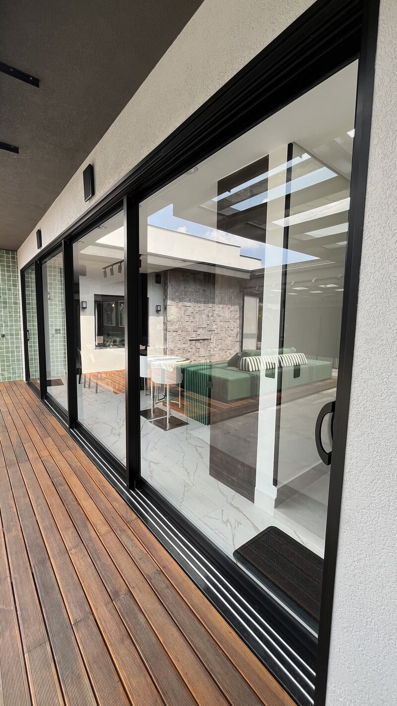 Porta de correr em grande vão integrando sala e deck de madeira